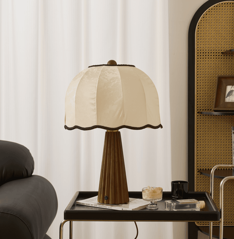 Scalloped shade lamp unlit on a tray table beside a leather sofa