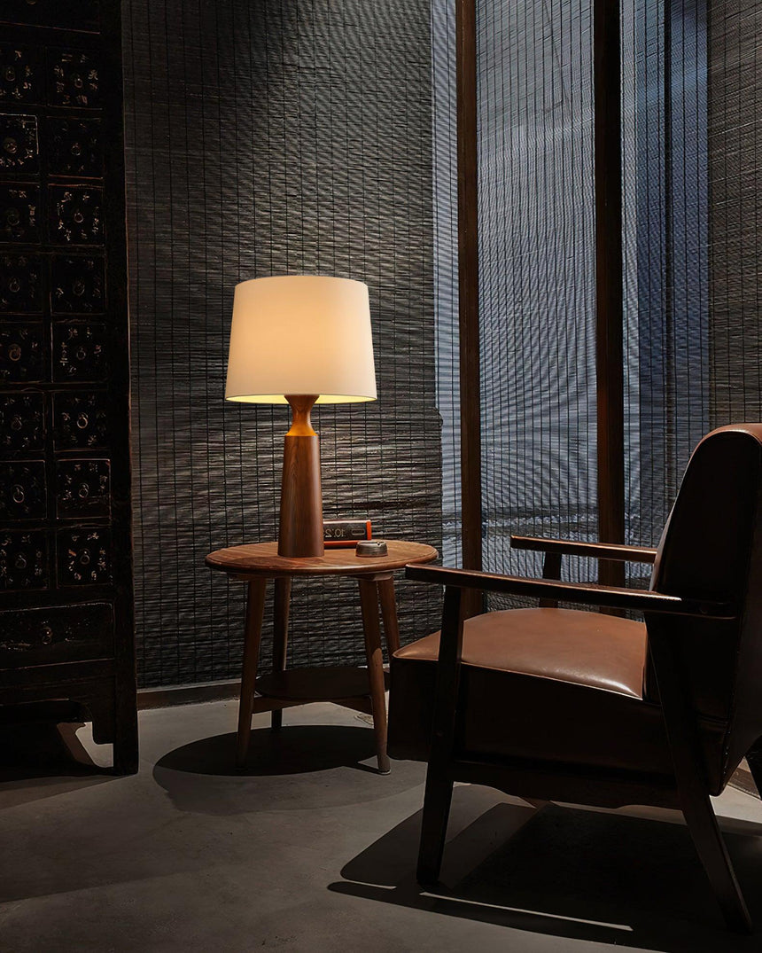 Console table lamp lit on a side table beside a leather chair