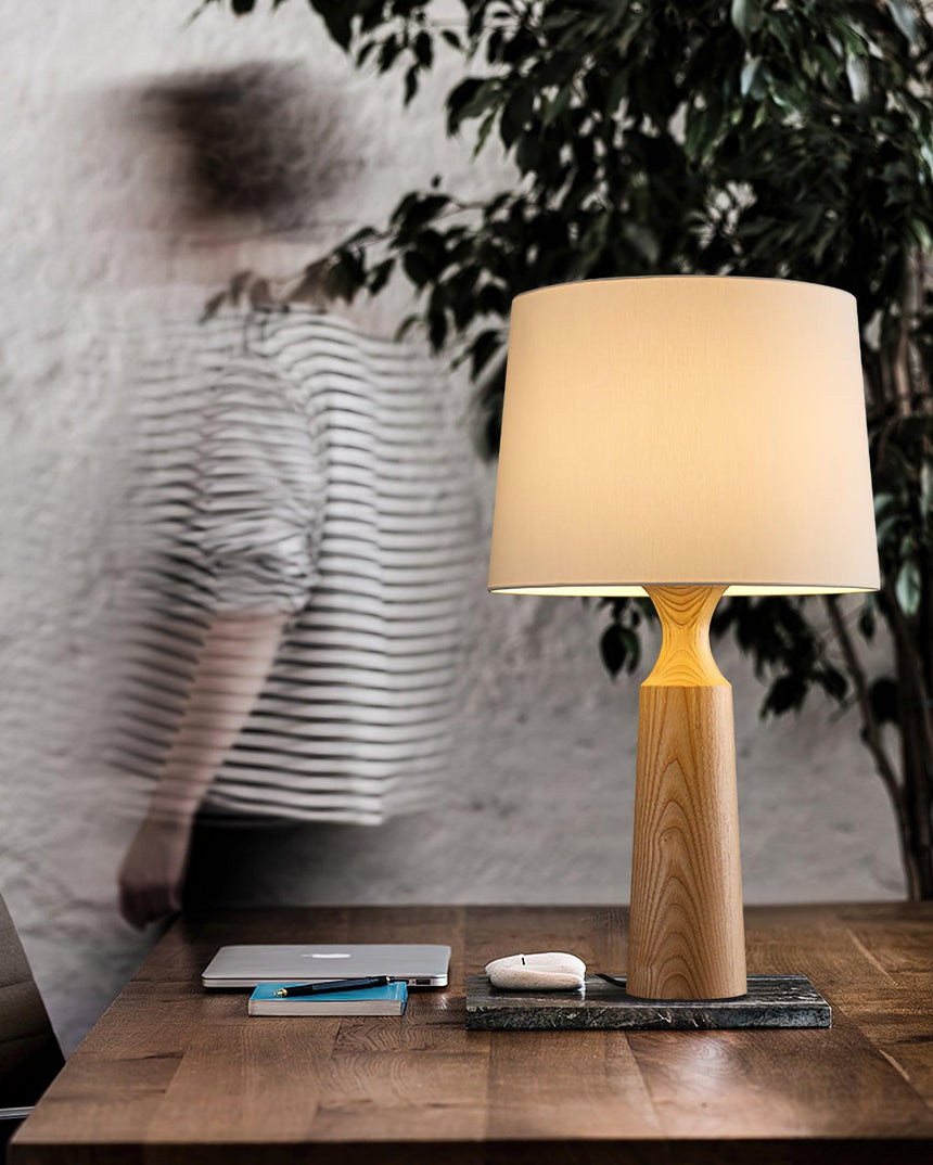 Console table lamp lit on a desk as someone walks past