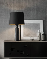 Console table lamp in black on a sideboard beside framed prints