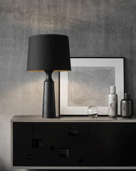 Console table lamp in black on a sideboard beside framed prints