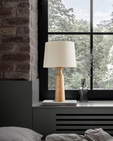 Console table lamp with a white shade lit on a windowsill