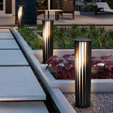 Two lit at the edge of a raised planter beside a paved terrace walk