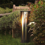 One lit in front of a stone bench with dense planting either side