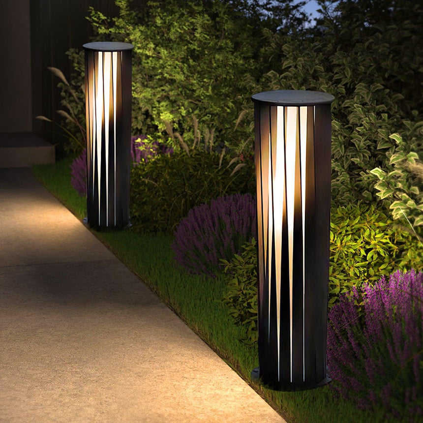Two lit along a paved walk beside a border of low purple planting