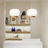 Pair of white glass shades in front of a pale shelving wall