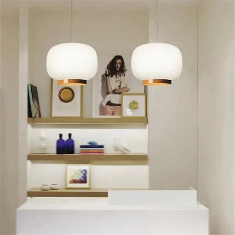 Pair of white glass shades in front of a pale shelving wall