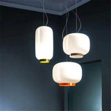 Three white glass shades hung at different heights on a dark wall