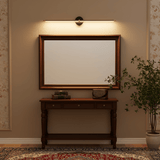 Gold rod lit above a framed mirror over a dark console table and a rug