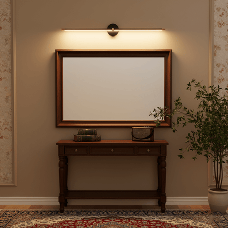 Gold rod lit above a framed mirror over a dark console table and a rug