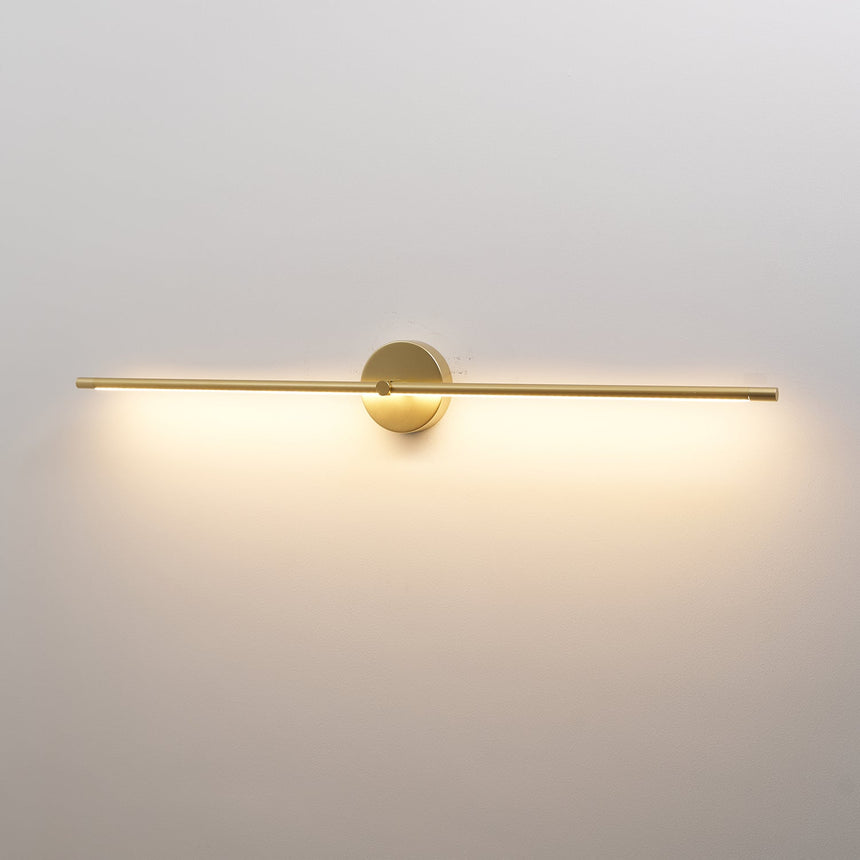 The gold rod lit against a pale wall, a soft wash spreading below the tube