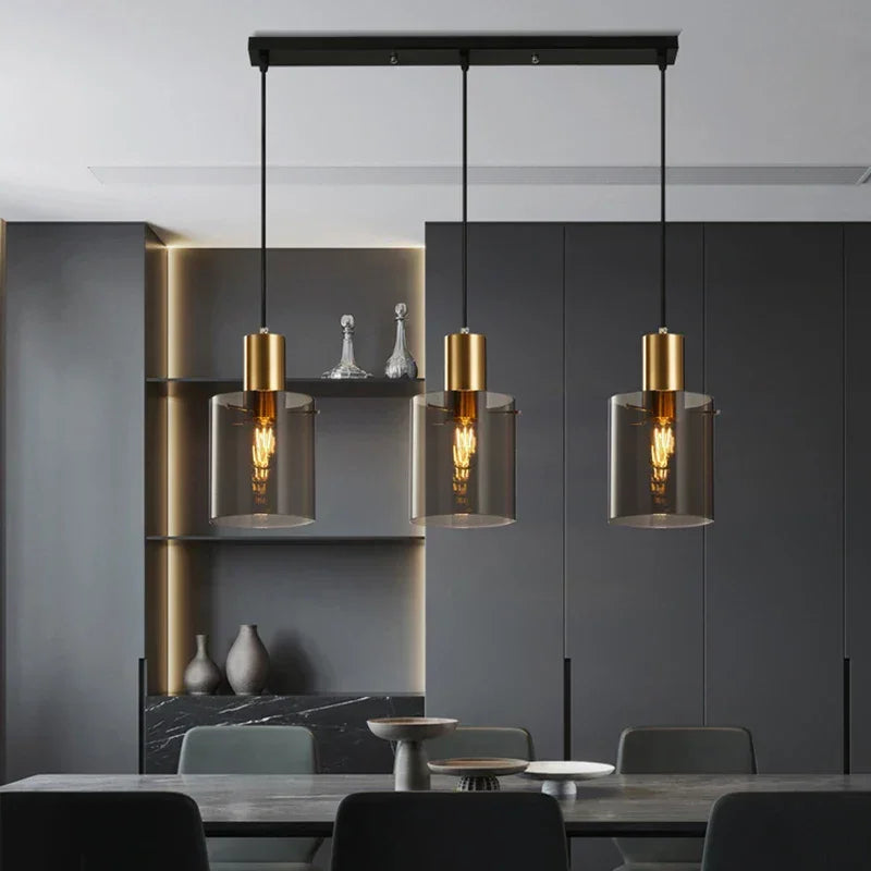 Three copper and smoked glass pendants lit above a dining table in a dark room