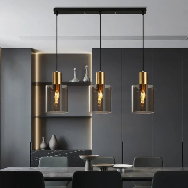Three copper and smoked glass pendants lit above a dining table in a dark room