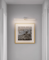 Black bar lit above a gilt framed landscape in a narrow hallway beside a doorway