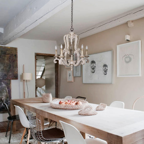 Lit above a long pale table and chairs in a room with a beamed white ceiling