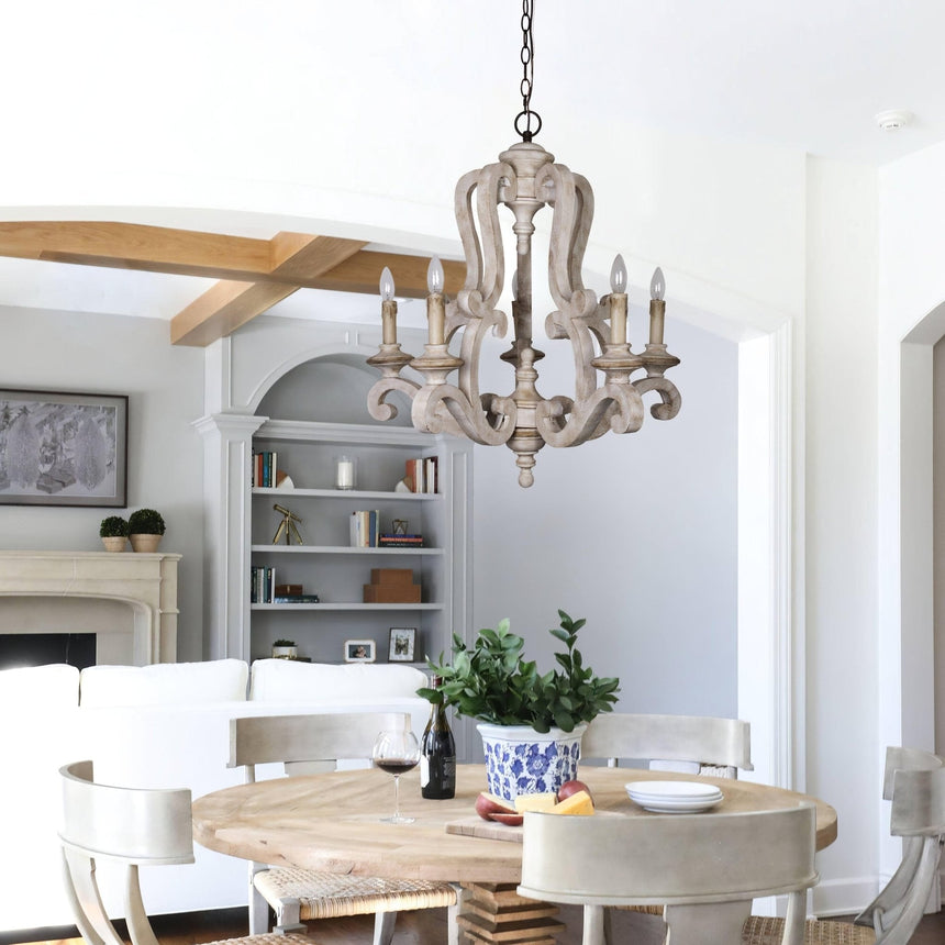 Seen over a round table in an open room with bookshelves and a fireplace beyond