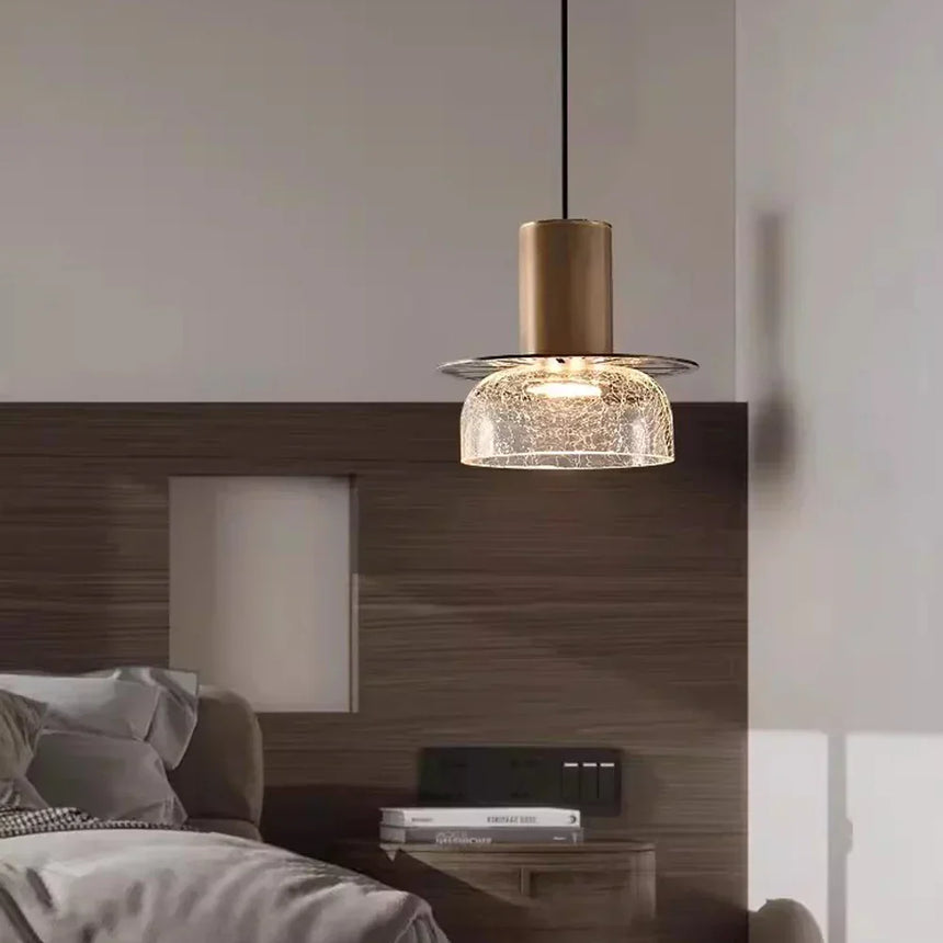A crackle glass pendant lit on a wooden bedroom wall above a low unit