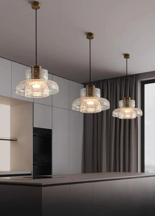 A row of crackle shades lit above a counter in a pale modern kitchen