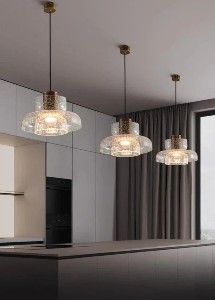 A row of crackle shades lit above a counter in a pale modern kitchen