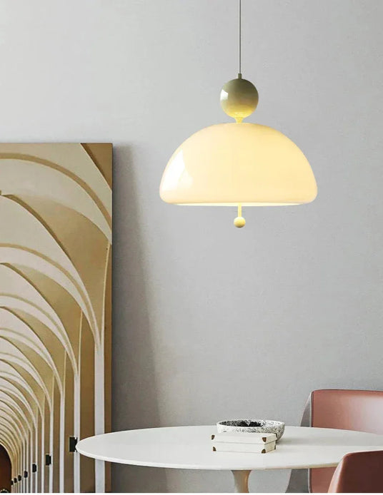 The cream dome lit above a round white dining table with curved chairs