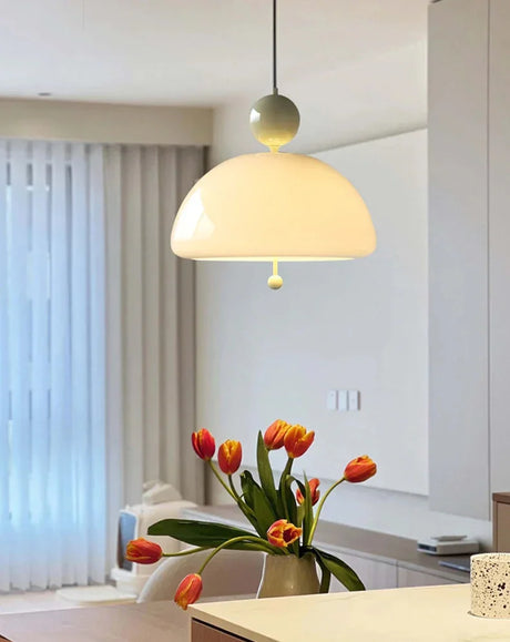 The cream dome lit above a table with orange tulips and a pale curtain behind