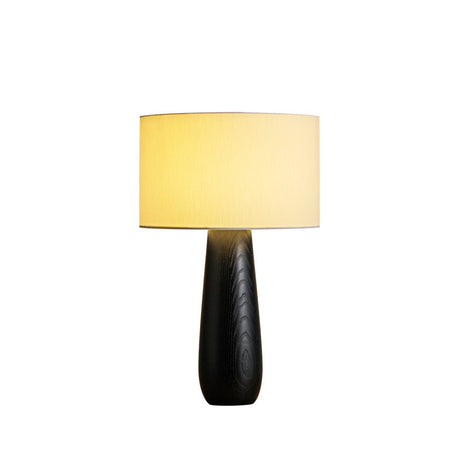 Cream table lamp on a black turned base, lit on a plain ground