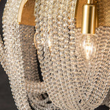 The crystal bead strands and one lit bulb seen close inside a gold arc