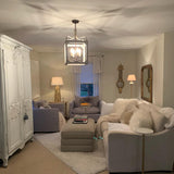 Lit in a room with a painted armoire, armchairs and a pale rug