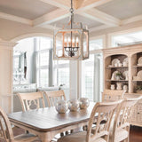 Lit above a pale dining table and chairs under a coffered ceiling with a dresser
