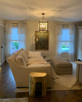 Lit in a living room between two windows above a sofa with artwork behind