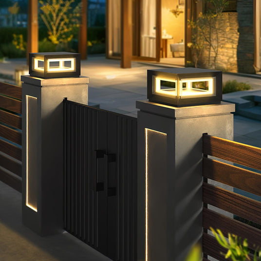 Two open frame cubes lit on gate posts beside a timber slat fence