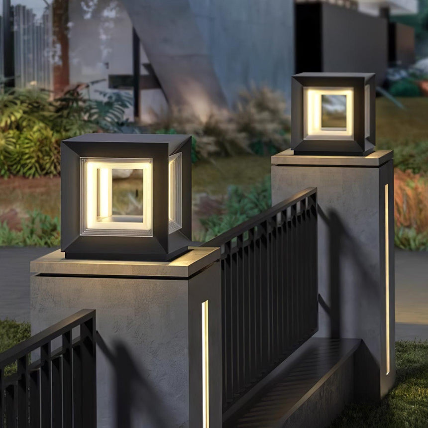 A row of lit cubes along pillars above a dark fence in a garden