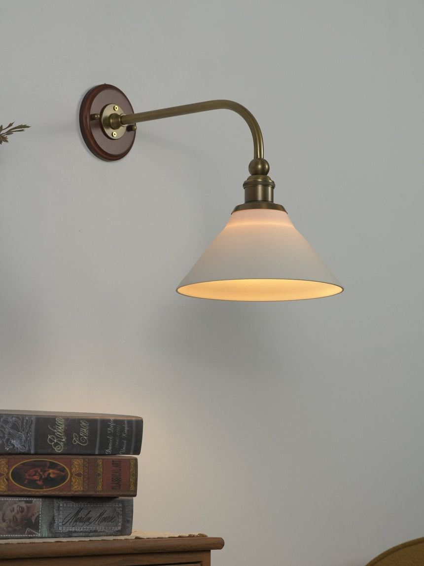 The white cone shade glowing at the end of the curved brass arm