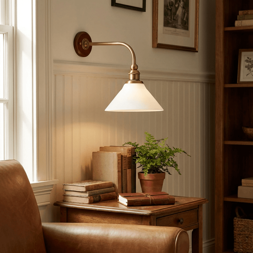 The sconce above a side table with books and a fern beside a leather armchair