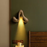 Sconce lit on a green wall beside a wood headboard and a bedside cup