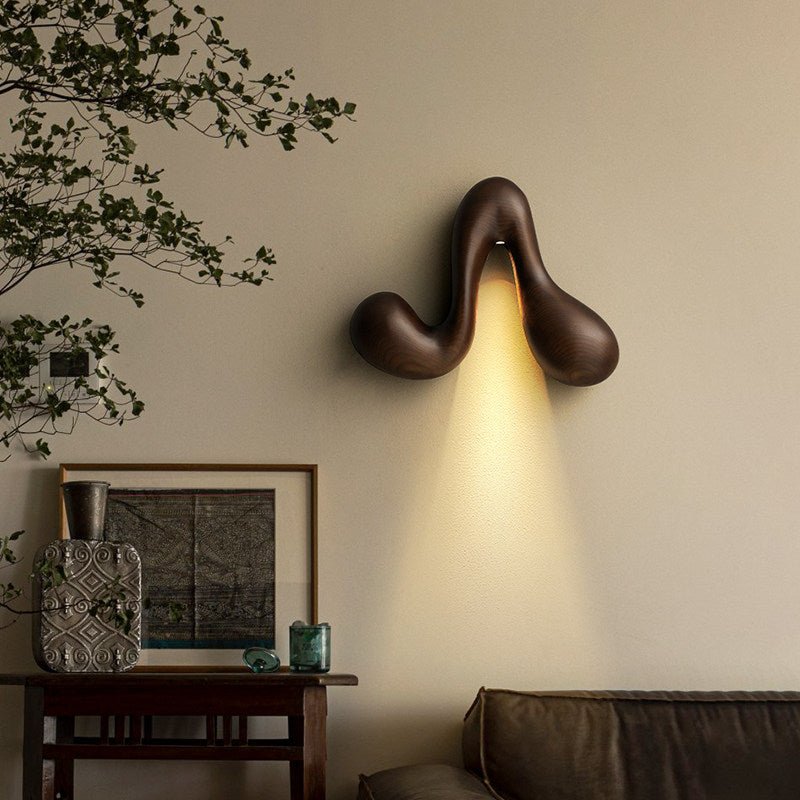 Sconce lit above a console with framed art, a plant and a low sofa
