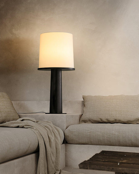 The black version lit beside a pale sofa and cushions