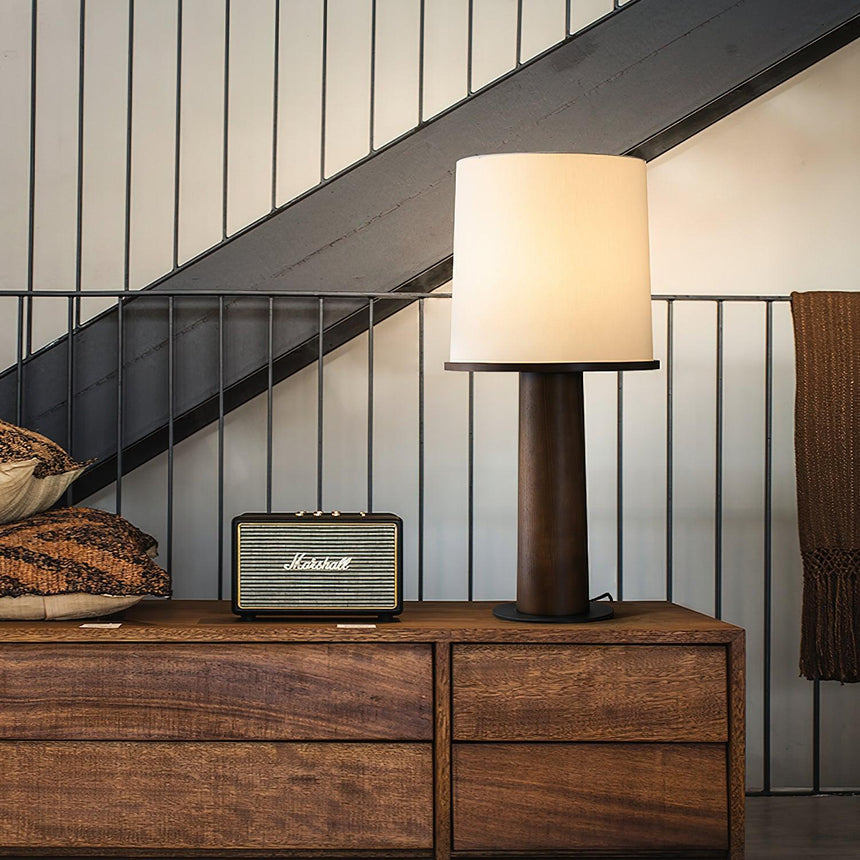 Cylinder table lamp lit on a dresser beside a metal staircase