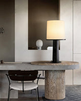 The black version lit on a stone table beside dining chairs