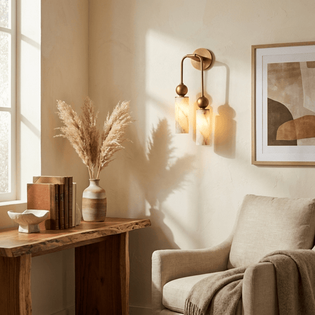 The light beside framed art above a console and a cream armchair