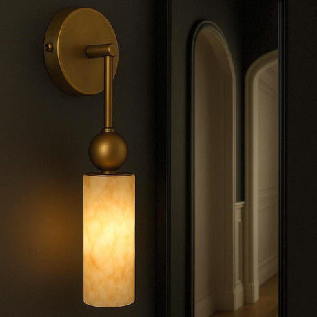 A single cylinder glowing warm on a dark wall beside a doorway