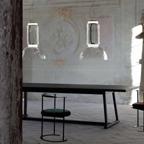 Two stacked cylinder pendants lit above a console with a chair