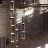 Two tall cylinder pendants lit against a carved stone wall