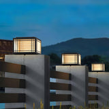 Two caps lit on pillars with hills and an evening sky behind them