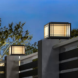 Caps lit on two pillars against a deep blue sky above a garden