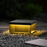 Light spilling from under the box onto gravel and a paving stone at night