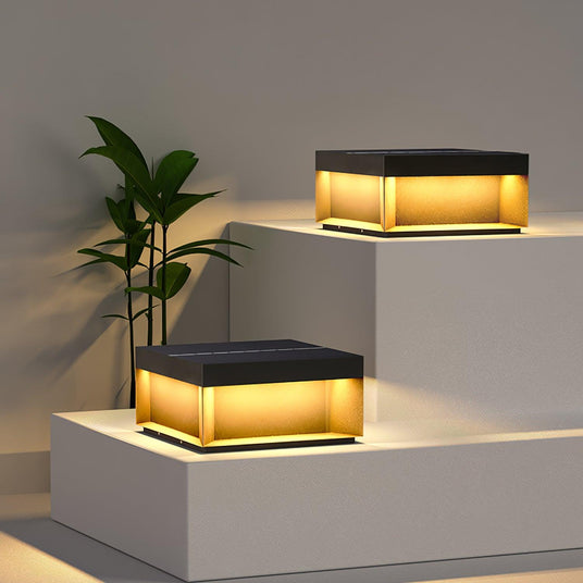 Two flat post lights glowing on pale garden steps beside a potted plant