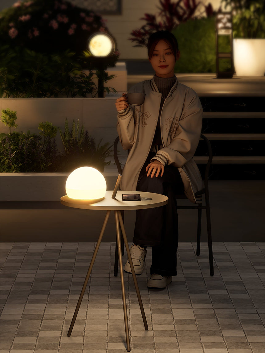 The tripod table lit on patterned courtyard tiles beside a low chair