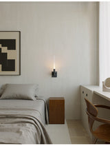 Lit beside a bed with a nightstand, a framed print and a chair in the corner