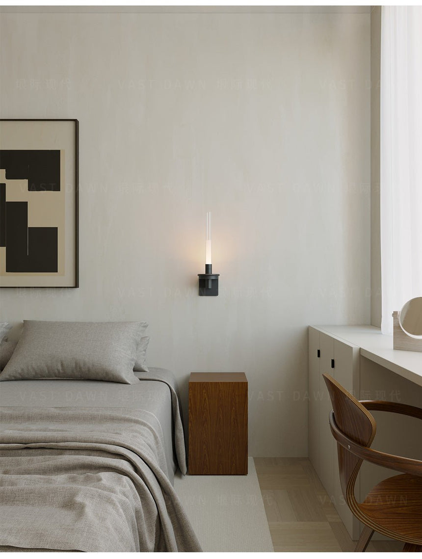 Lit beside a bed with a nightstand, a framed print and a chair in the corner